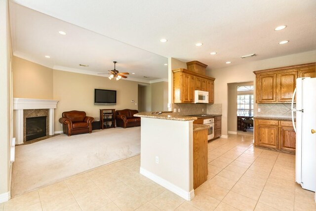 kitchen featuring light stone counters, white appliances, tasteful backsplash, ceiling fan, and light colored carpet