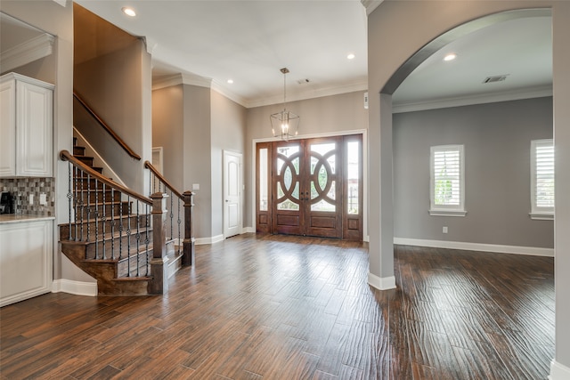 entryway with an inviting chandelier, dark hardwood / wood-style floors, and ornamental molding