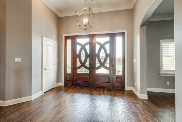 foyer entrance featuring dark hardwood / wood-style flooring, crown molding, and a chandelier