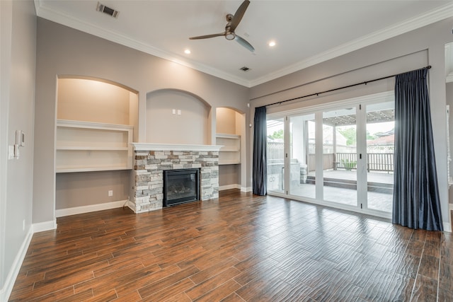 unfurnished living room with a stone fireplace, ornamental molding, built in shelves, dark hardwood / wood-style floors, and ceiling fan