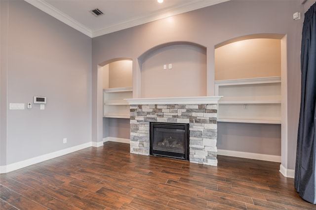 unfurnished living room with crown molding, a stone fireplace, built in shelves, and dark hardwood / wood-style floors