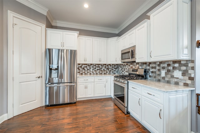 kitchen featuring dark wood-type flooring, tasteful backsplash, ornamental molding, white cabinetry, and stainless steel appliances