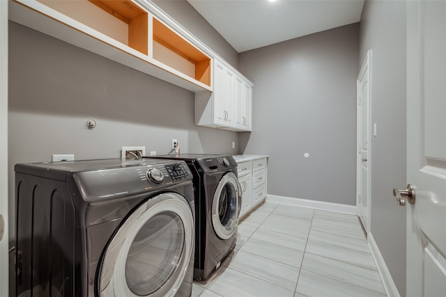 laundry area with washer and dryer, cabinets, and light tile patterned flooring