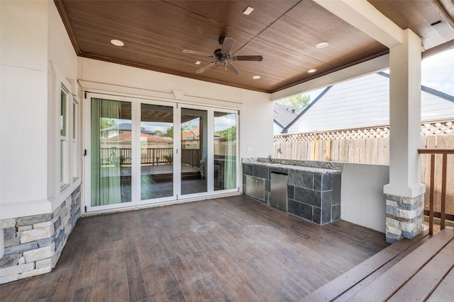 wooden terrace with ceiling fan and an outdoor kitchen