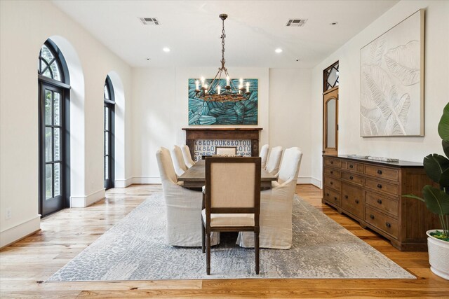 dining room featuring a wealth of natural light, light wood-type flooring, and an inviting chandelier