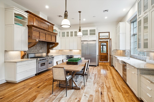 kitchen featuring light hardwood / wood-style floors, high quality appliances, light stone countertops, and tasteful backsplash