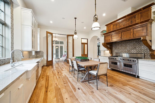 kitchen with a wealth of natural light, backsplash, light wood-type flooring, and double oven range