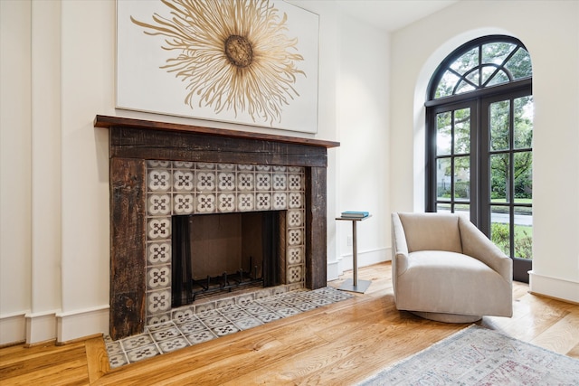 sitting room with a wealth of natural light, a tiled fireplace, and light hardwood / wood-style flooring