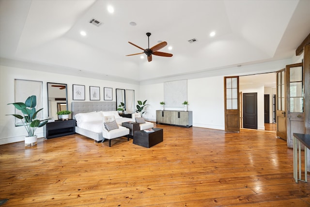 living room with ceiling fan, a raised ceiling, and light wood-type flooring