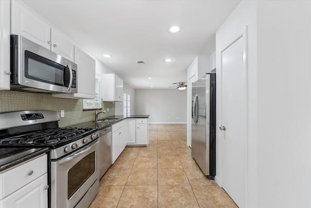 kitchen featuring ceiling fan, tasteful backsplash, white cabinets, light tile patterned floors, and stainless steel appliances