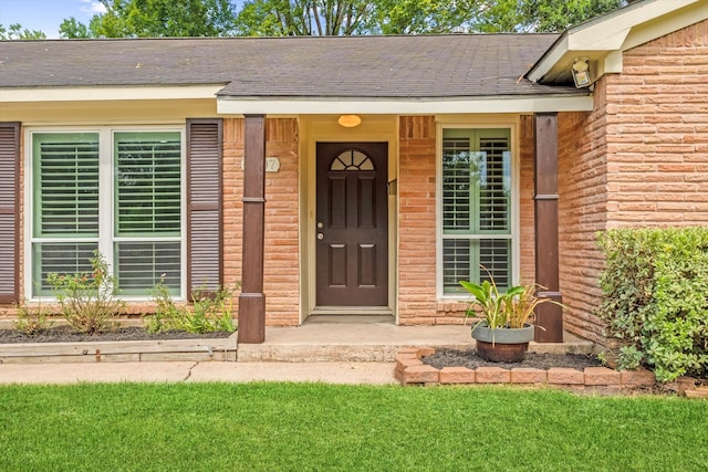 view of exterior entry featuring a lawn