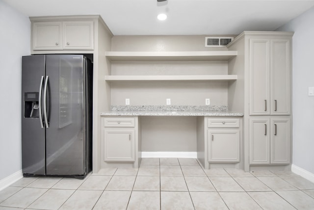 kitchen featuring stainless steel fridge, light stone countertops, and light tile patterned floors