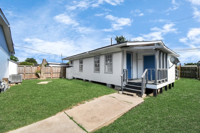 rear view of property with central AC and a yard