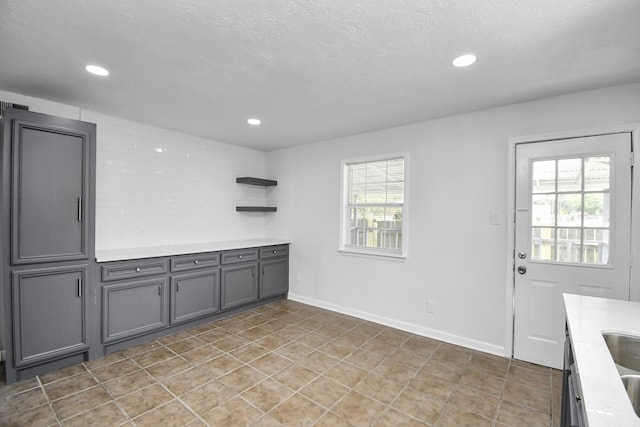 unfurnished dining area with light tile patterned floors, sink, and a textured ceiling