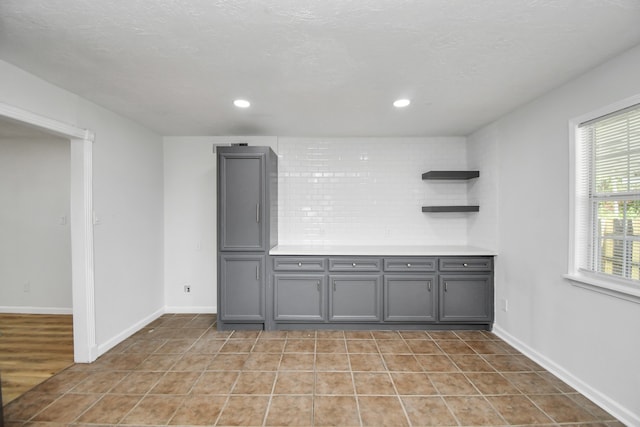 bar featuring tasteful backsplash, light hardwood / wood-style flooring, and gray cabinetry