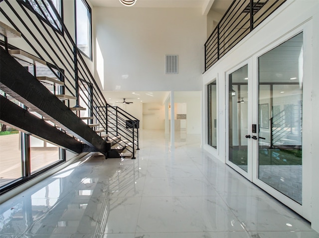 staircase featuring french doors and a high ceiling