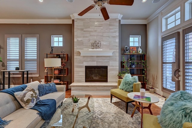 living room with ornamental molding, a healthy amount of sunlight, a fireplace, and ceiling fan