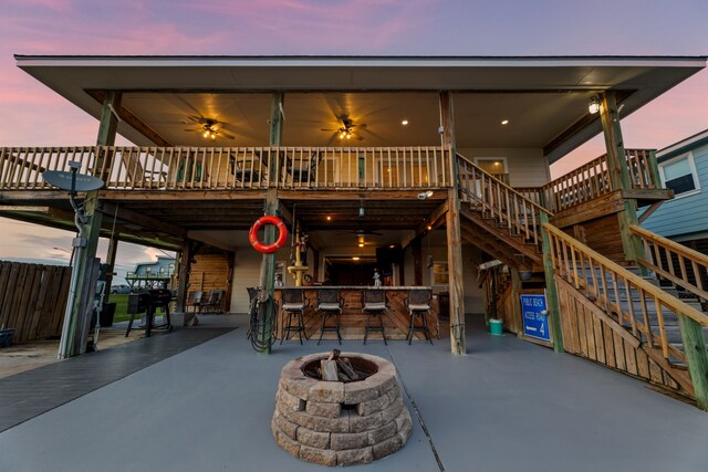 back house at dusk featuring a patio, a fire pit, and an outdoor bar