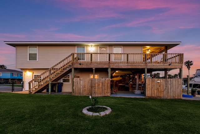 back of house at dusk with stairs, a yard, and a deck