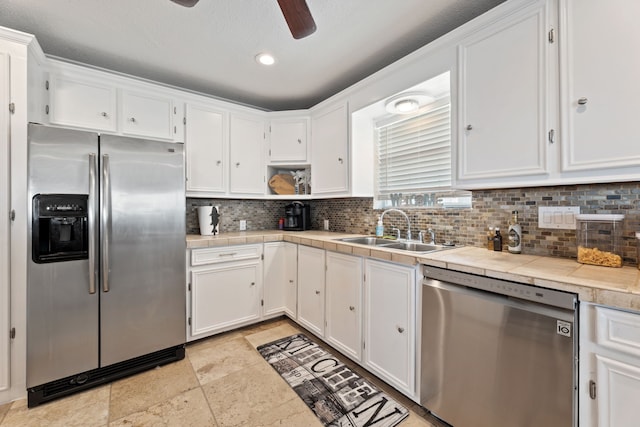 kitchen with open shelves, stainless steel appliances, tile counters, white cabinetry, and a sink