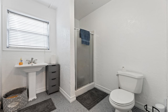 bathroom with toilet, a shower stall, baseboards, and a textured wall