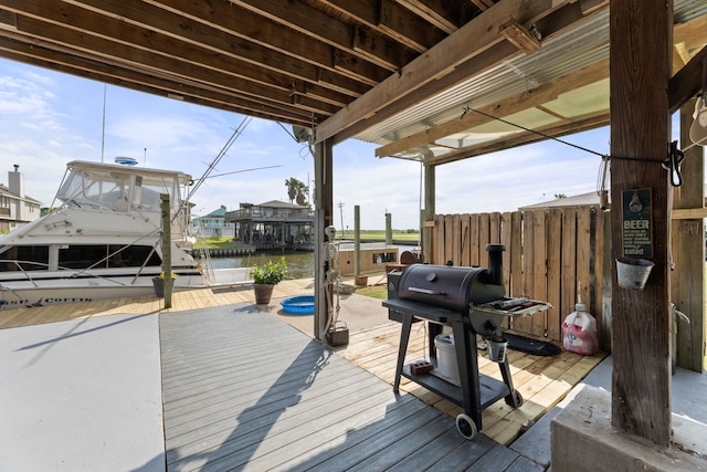 deck featuring boat lift, a boat dock, a water view, and a grill