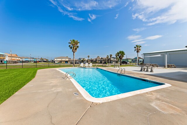 community pool featuring a lawn, a patio area, and fence