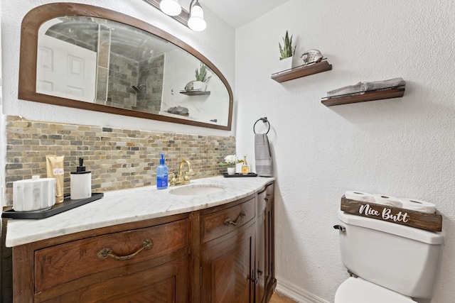 bathroom featuring a textured wall, toilet, backsplash, and vanity