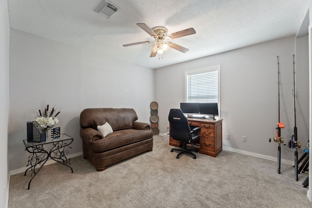 office space featuring light carpet, a ceiling fan, visible vents, and a textured ceiling