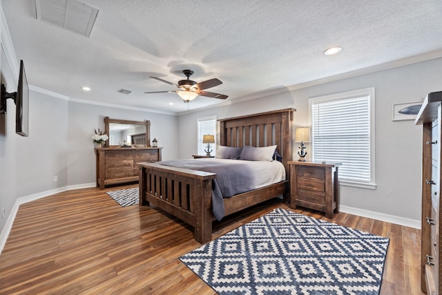 bedroom with baseboards, crown molding, visible vents, and wood finished floors