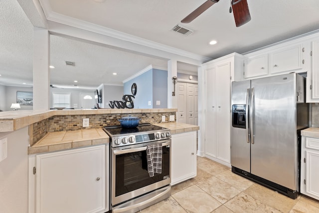 kitchen with stainless steel appliances, tile counters, white cabinets, and visible vents