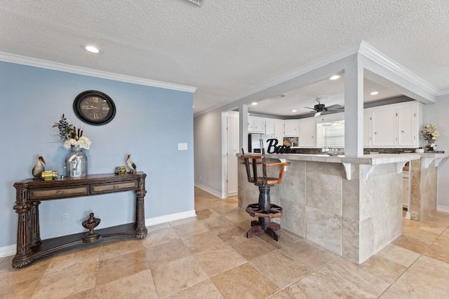 bar with ornamental molding, baseboards, a textured ceiling, and stainless steel fridge with ice dispenser