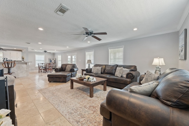 living area featuring a healthy amount of sunlight, visible vents, crown molding, and light tile patterned floors