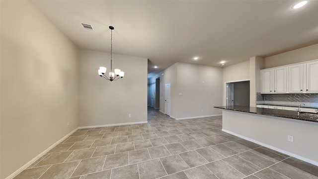 kitchen featuring visible vents, decorative backsplash, dark stone countertops, decorative light fixtures, and white cabinetry