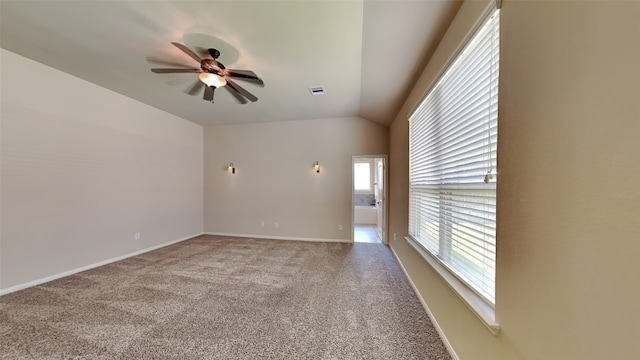 carpeted spare room featuring vaulted ceiling, baseboards, visible vents, and a ceiling fan