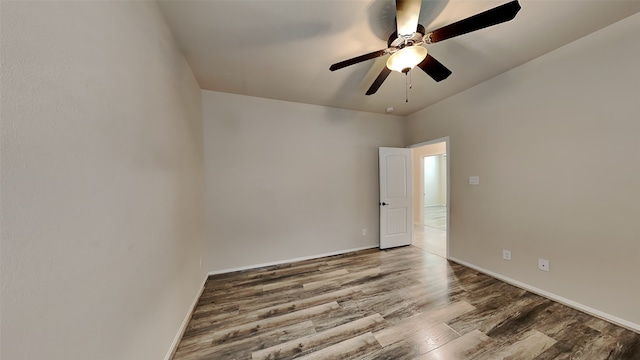 spare room with wood finished floors, a ceiling fan, and baseboards