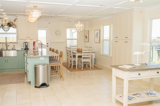 kitchen with a kitchen island, a sink, white cabinetry, tasteful backsplash, and pendant lighting