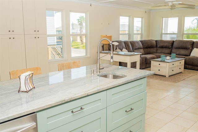 kitchen with light stone counters, a sink, open floor plan, plenty of natural light, and crown molding