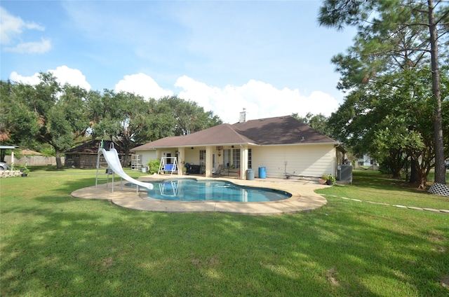 view of swimming pool featuring a patio area, a water slide, central AC unit, and a yard