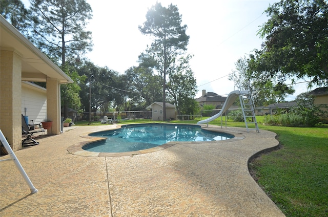 view of pool with a lawn, a storage unit, a patio area, and a water slide