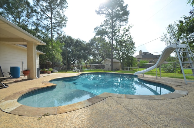 view of pool featuring a storage unit, a water slide, a patio area, and a playground