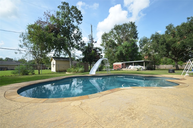 view of swimming pool with a patio area, a water slide, an outdoor structure, and a yard