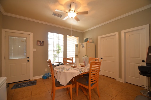 tiled dining area with ceiling fan and ornamental molding