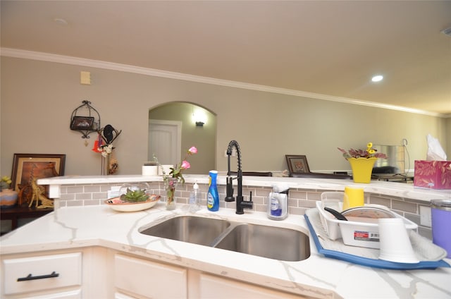 kitchen with decorative backsplash, sink, crown molding, and light stone counters