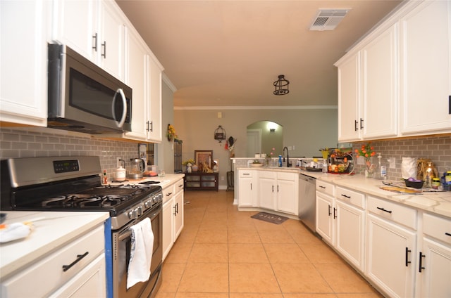 kitchen featuring light tile patterned flooring, appliances with stainless steel finishes, ornamental molding, and backsplash