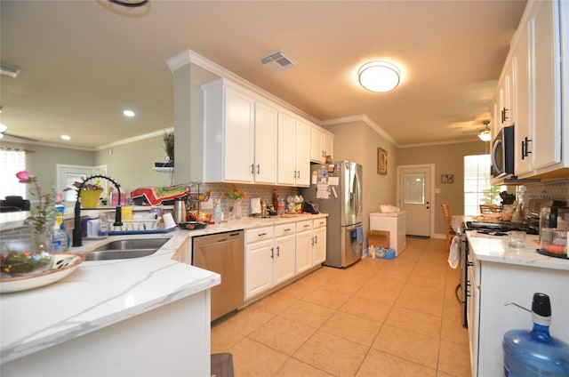 kitchen with backsplash, appliances with stainless steel finishes, light stone countertops, light tile patterned floors, and white cabinets