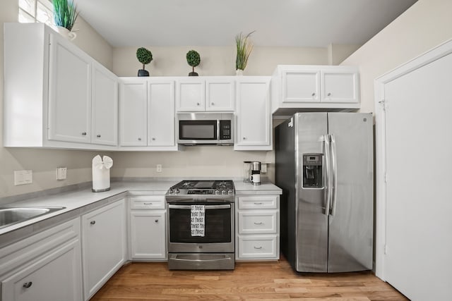 kitchen with white cabinets, light hardwood / wood-style floors, and stainless steel appliances