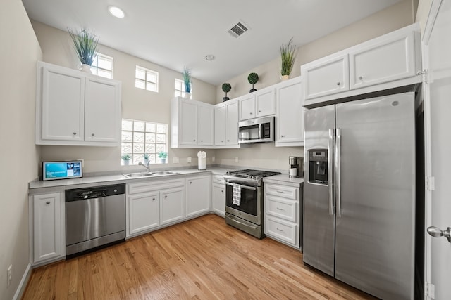 kitchen featuring sink, stainless steel appliances, light hardwood / wood-style flooring, and white cabinets