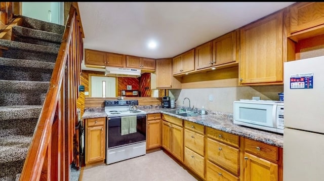 kitchen featuring light stone countertops, white appliances, and sink