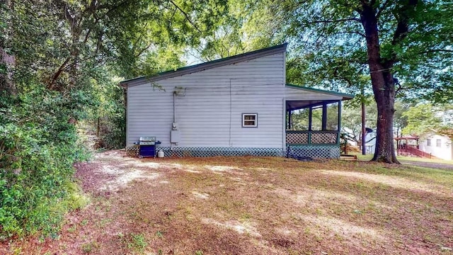 view of side of home featuring a sunroom and a lawn